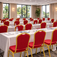 Konferenčná stolička s červeným čalúnením a zlatým rámom.