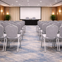 Konferenčná stolička so sivým čalúnením a strieborným rámom.