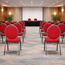 Konferenčná stolička s červeným čalúnením a čiernym rámom.